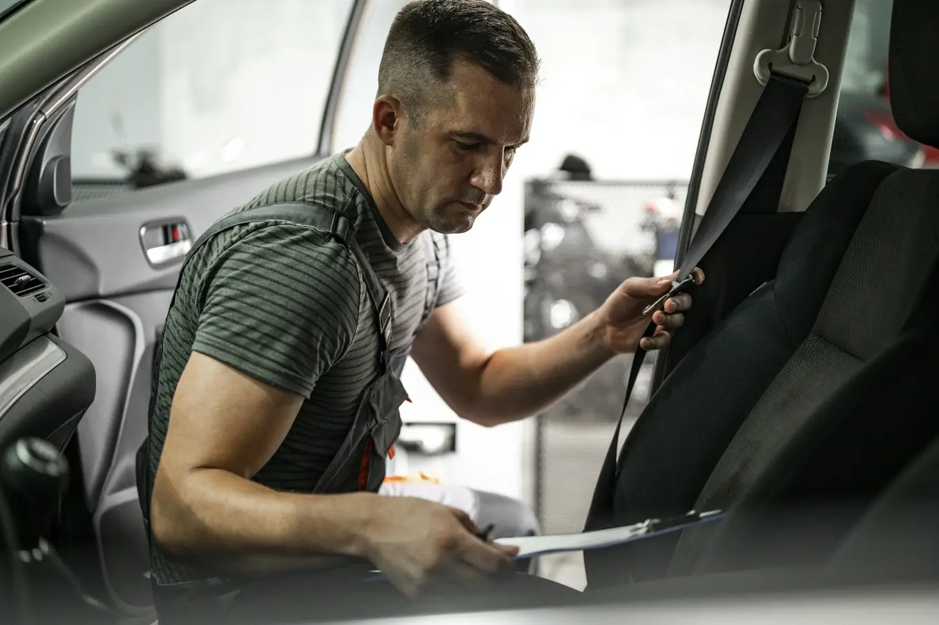 mechanik sprawdzający pasy bezpieczeństwa w samochodzie